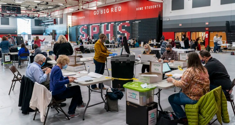 Poll worker Rebecca Brandt, center, feeds a voting tabulation machine with absentee ballots in the gym at Sun Prairie High School on Nov. 3 in Sun Prairie. The entire gym was dedicated to counting the absentee ballots. (Photo by Andy Manis/Getty Images)