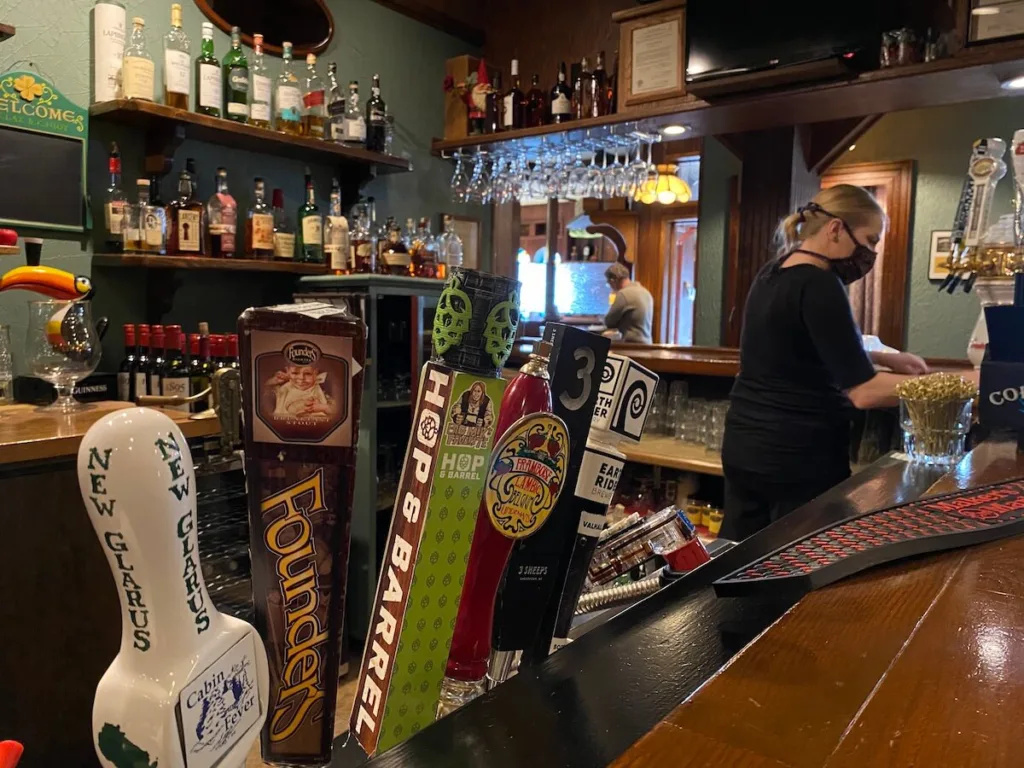 Ashley Deetz cleans the bar area at Houligans Steak & Seafood Pub in downtown Eau Claire Thursday afternoon before the restaurant opened. People working at restaurants, taverns and other service sector jobs have been among the hardest hit financially by the ongoing coronavirus pandemic. (Photo by Julian Emerson)
