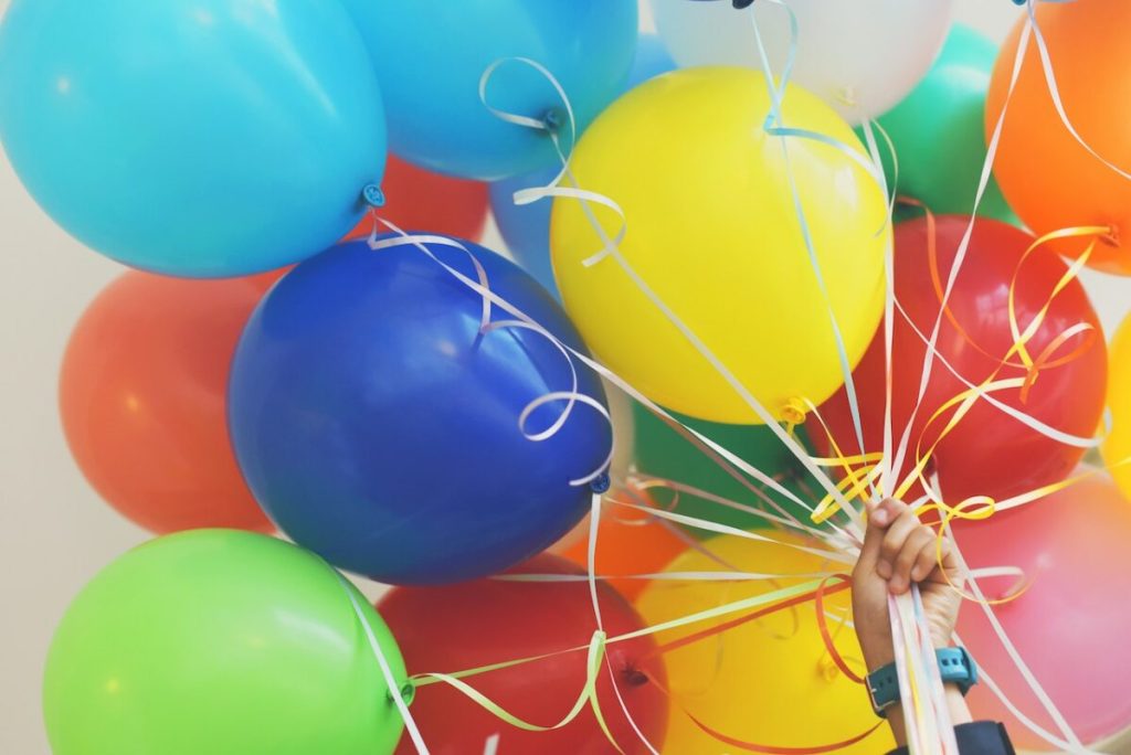 Hand holding a colorful array of balloons.