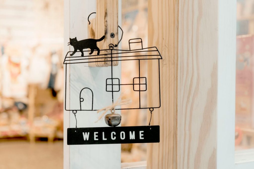 Welcome sign with a small black cat on top of the sign.