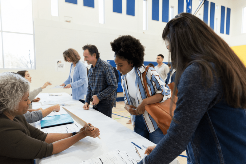 Photo of Polling place volunteers assisting voters with voting documents