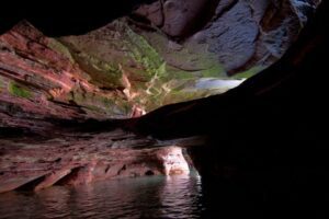 A cave formation with sunlight beaming through onto the water.