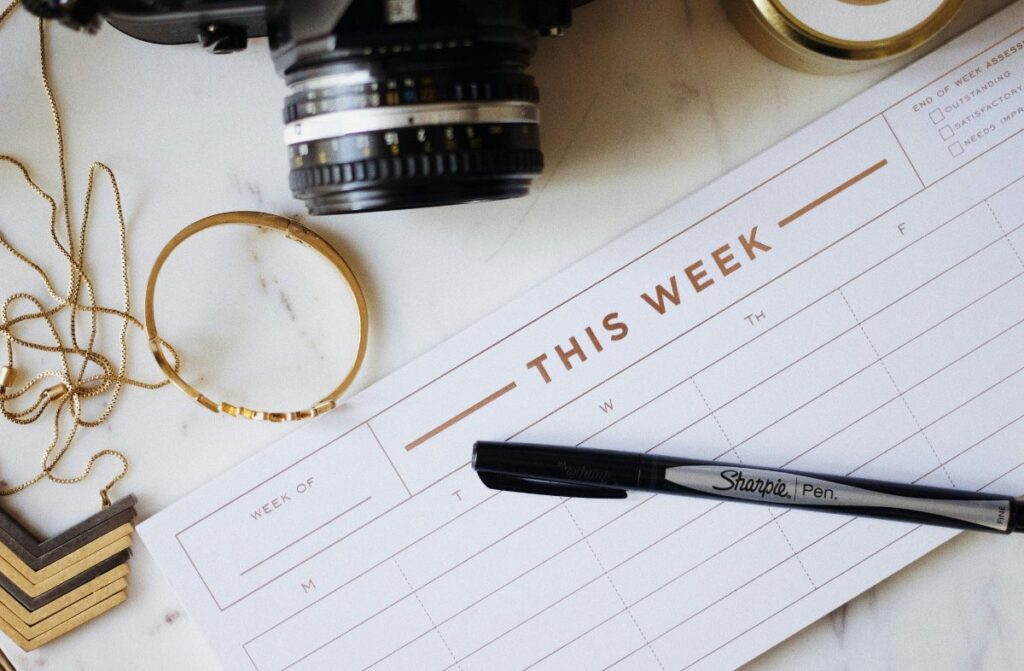 Weekly planner with pen, jewelry, and a camera.