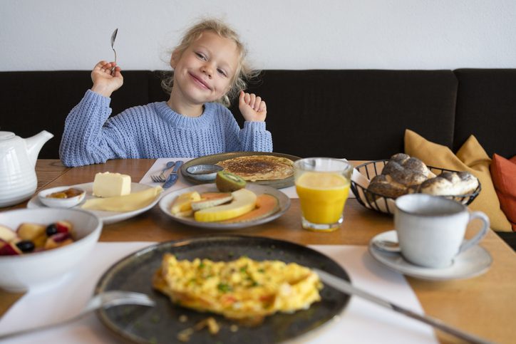 Smiling girl having breakfast in a restaurant