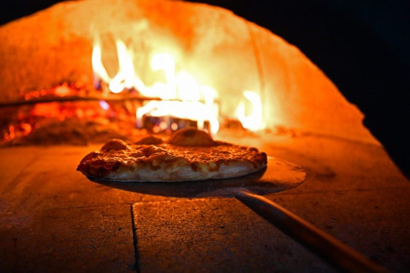 A pizza inside a wood-fired oven.