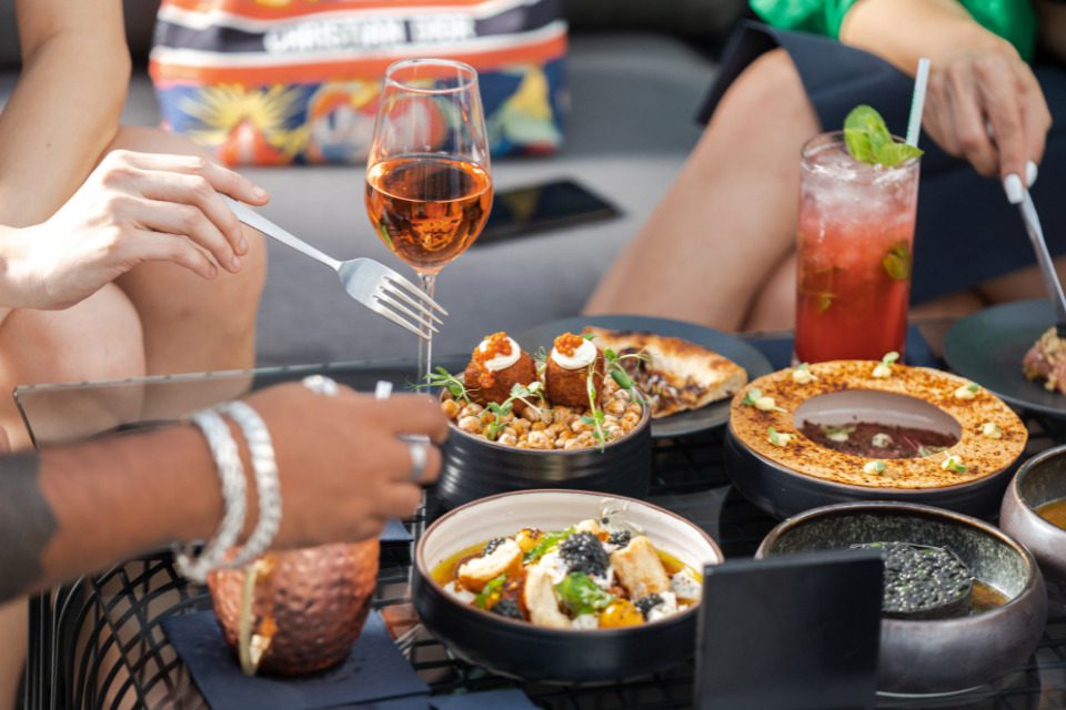 People sharing food at an outdoor table at a restaurant.