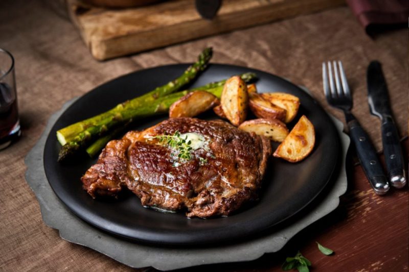 A plate of steak, potatoes, and asparagus at a supper club