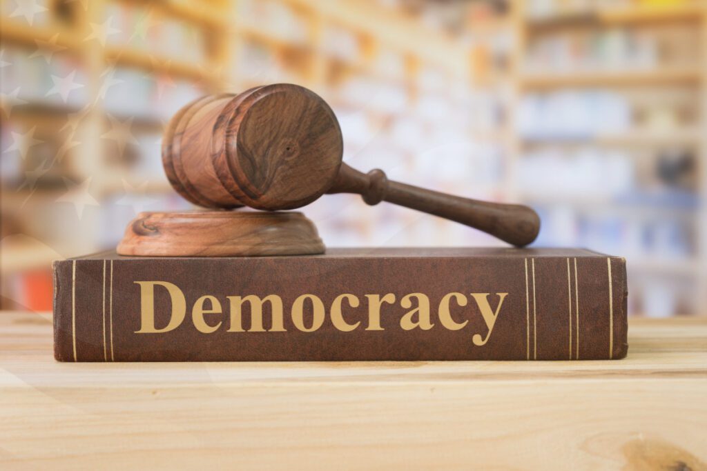 Opinion: The danger of political intimidation Gavel on top of book that says Democracy