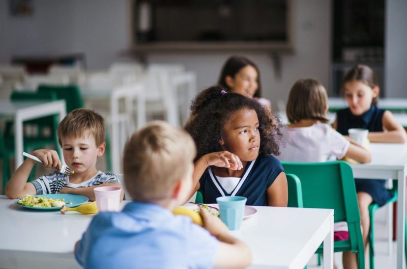 Young children sitting at a table having lunch.