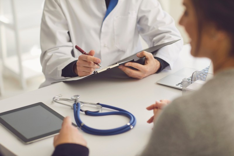 Medicaid. Couple Patient Sitting at the Table in Clinic Office talking to doctor.