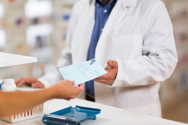 Arm handing prescription paper to pharmacist for obesity treatment medication.