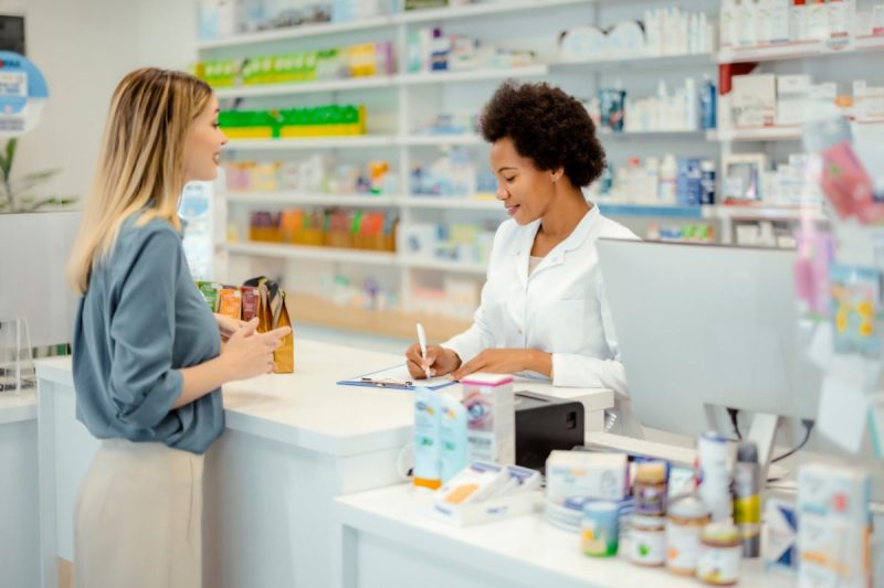 birth control. Pharmacy Drugstore: Female Cashier in White Coat Serves Customer. Medicine Recommendation, Advice, Talking. Drugstore With Full of Drugs, Pills