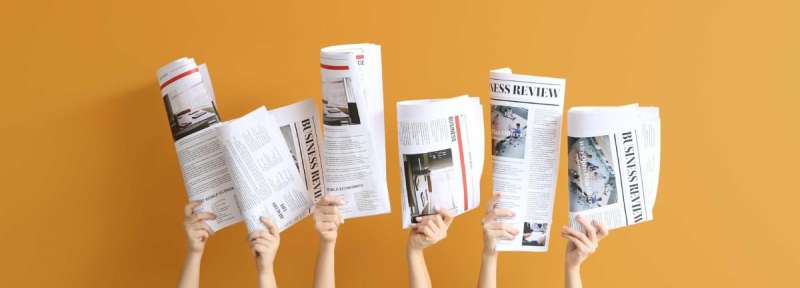 Hands holding newspaper headlines