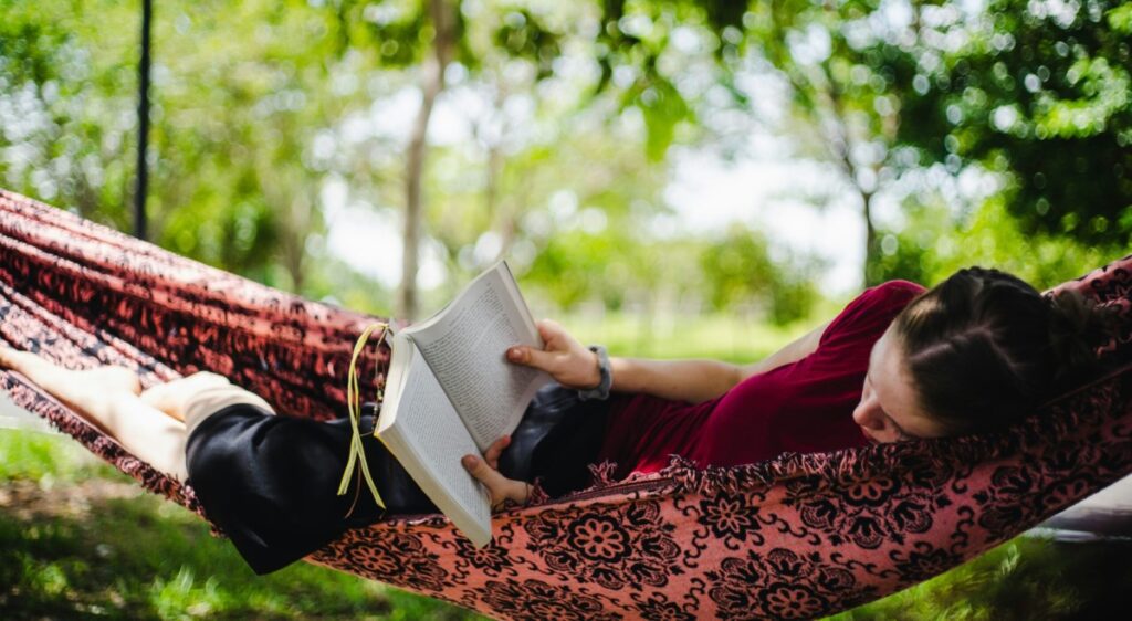 person reading a book in a hammock outside