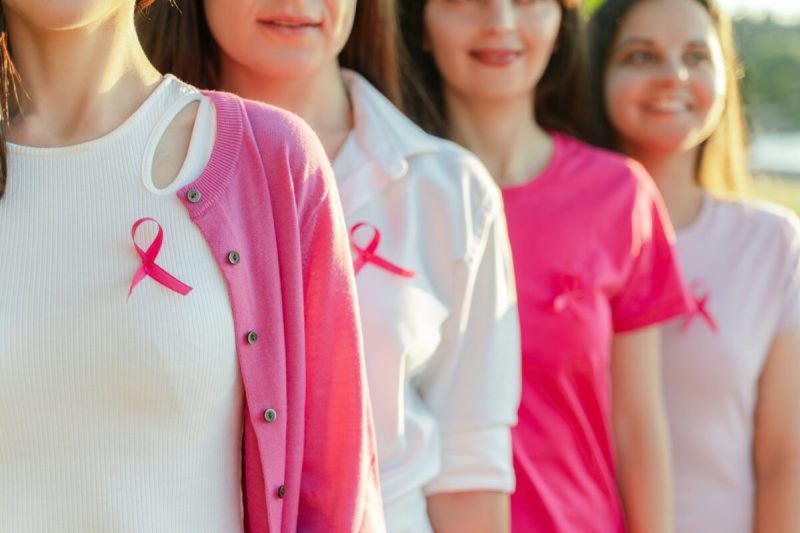 Women wearing breast cancer awareness ribbons, commonly seen during Breast Cancer Awareness Month