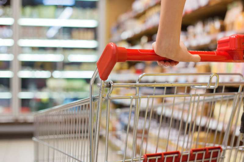Cart with red handle being pushed at the grocery store