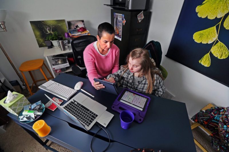 Mom helps daughter with virtual learning.