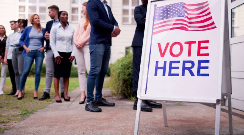 Vote Here sign. Voters standing in line