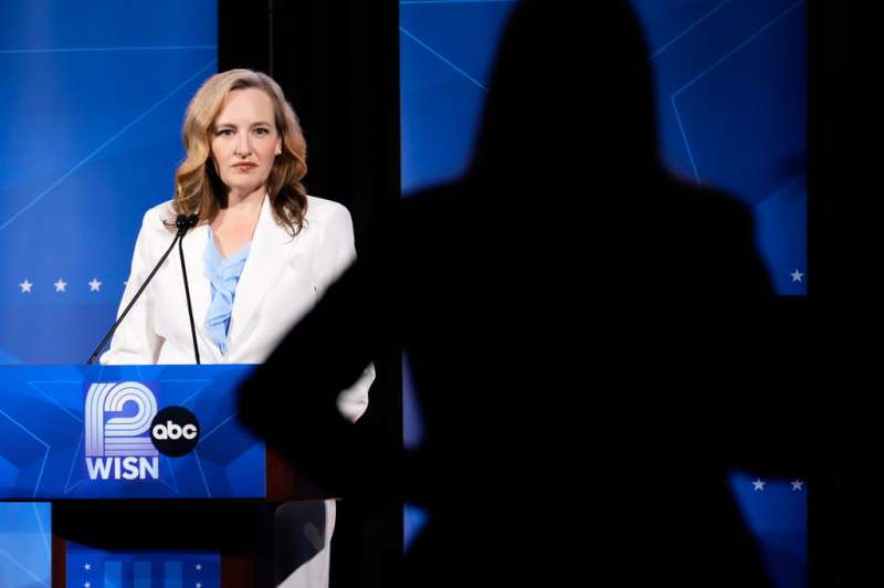 Woman in white suit standing and speaking at podium