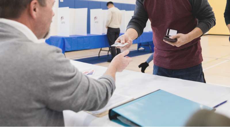 Voter handing photo ID to poll worker at polling location. (SDI Productions/Getty Images Signature)